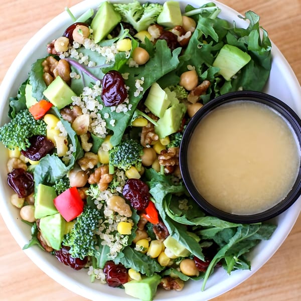 Bliss & Vinegar salad with greens, quinoa, avocado, chickpeas, corn, broccoli, walnuts, and dried cranberries.