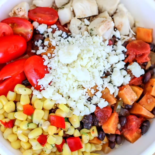A vibrant Bliss & Vinegar salad with chicken, corn, tomatoes, sweet potatoes, black beans, and feta.